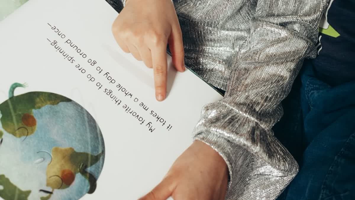 A child pointing at the text in an illustrated picture book